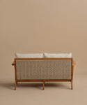 The Outdoor Vista Sofa features a wooden frame, woven rattan back, and two Tempotest fabric cushions. Photographed from behind, it is set against a plain beige background.