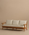 The Outdoor Vista Sofa is a mid-century modern teak piece with angled legs and armrests, including three off-white Tempotest fabric seat cushions and three matching back cushions, shown on a plain beige background.
