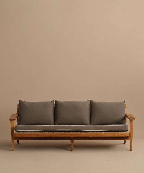The Outdoor Vista Sofa is a minimalist teak piece with three gray cushions and armrests, shown against a plain beige background—perfect as stylish ECOLENE furniture for modern outdoor spaces.