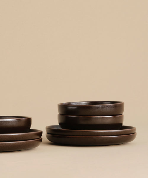 A Pacific Salad Plate in dark brown is neatly stacked on a beige surface with a plain beige background.