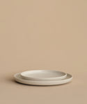 Two Pacific Salad Plates, simple and round, are stacked together on a neutral beige surface with a matching beige background.