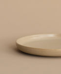 The Pacific Salad Plate, featuring a simple round design in beige, rests on a matching surface with a plain beige background.