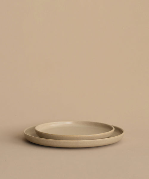 A pair of round beige stoneware dinner plates—a Pacific Salad Plate stacked inside a larger one—arranged on a plain beige background.