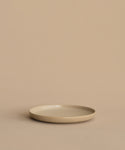 A Pacific Salad Plate, round and beige, rests on a matching surface with a beige background, forming a minimal and neutral scene.