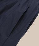 A close-up of dark navy blue Italian washed poplin fabric with gentle folds, set against a light beige background—ideal for creating the elegant Peninsula Dress.