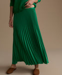 Green pleated skirt worn by a person on a beige background