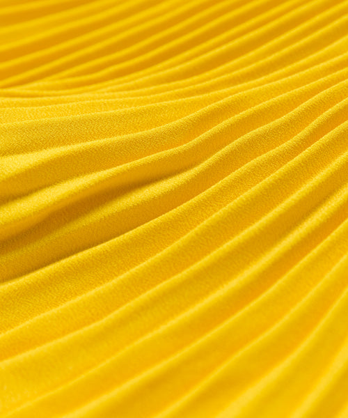Close-up of Pleated Skirt fabric in bright yellow, featuring soft texture with evenly spaced ridges and folds for a wavy, flattering drape.