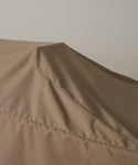 A close-up shows the brown Outdoor Vista Dining Table Cover, made of durable polyester, draped over furniture with sharp folds and angled lines set against a plain light background.