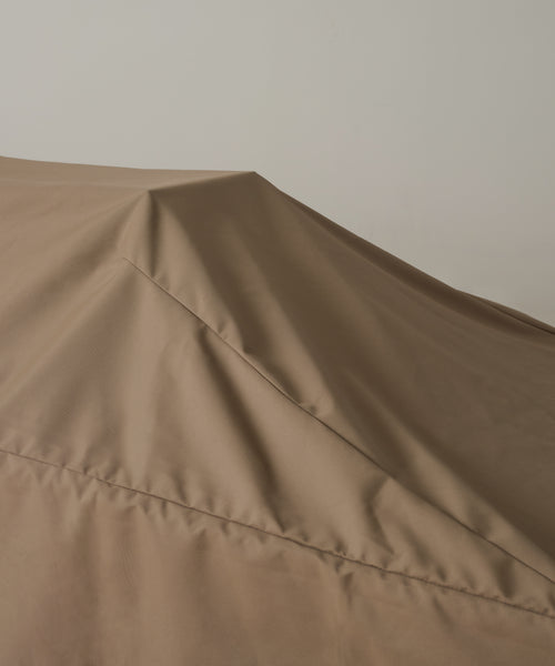 A close-up shows the brown Outdoor Vista Dining Table Cover, made of durable polyester, draped over furniture with sharp folds and angled lines set against a plain light background.