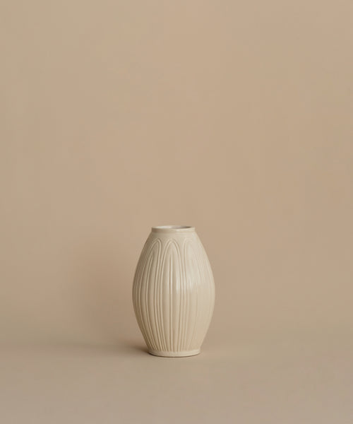 A small cream-colored ceramic vase with a textured vertical ribbed pattern, centered against a solid beige background.