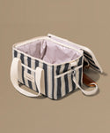 Striped cooler bag with white handles on a beige background