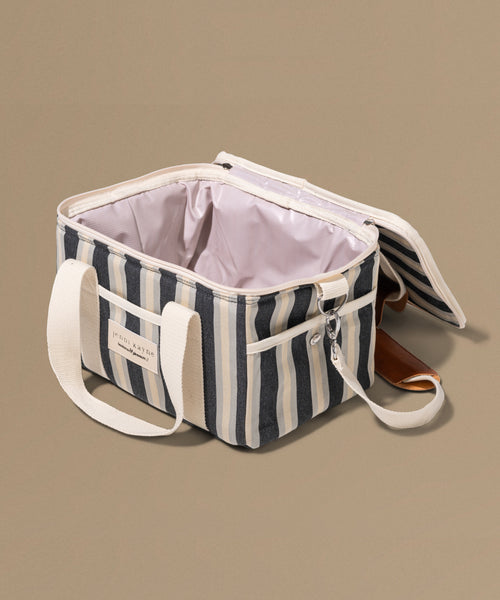 Striped cooler bag with white handles on a beige background