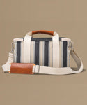 Striped bag with brown leather accents on a beige background