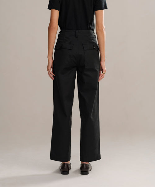 A person stands facing away from the camera, wearing a black t-shirt, fitted high-waisted Ranger Trouser with back pockets, and black shoes against a plain neutral background.