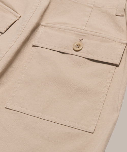 Close-up of the Ranger Trouser in beige, featuring a large side pocket with flap and button closure, detailed stitching, and part of the waistband—a classic design with practical style.