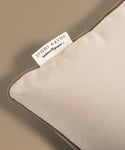 Close-up of a beige pillow with a Jenni Kayne label on a matching background