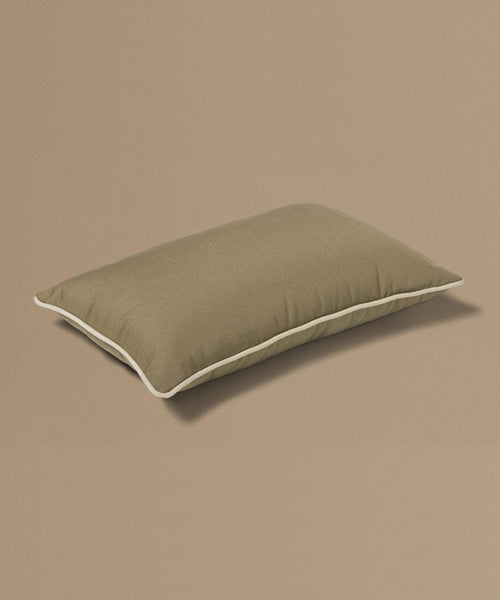 Brown pillow with a brand tag on a beige background