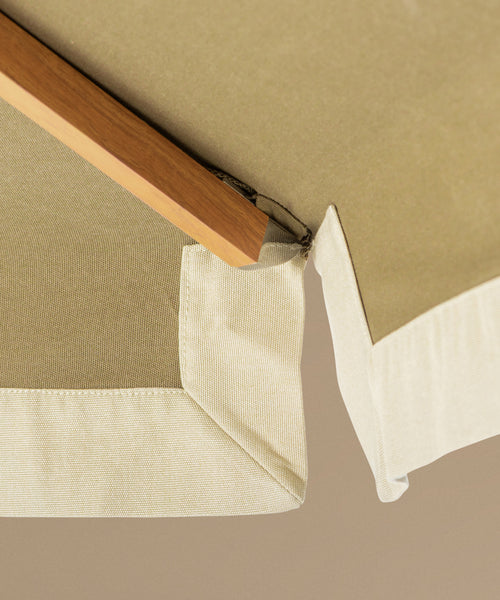 Green patio umbrella with a wooden handle on a beige background