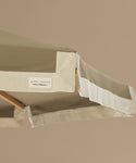Green patio umbrella with a wooden handle on a beige background