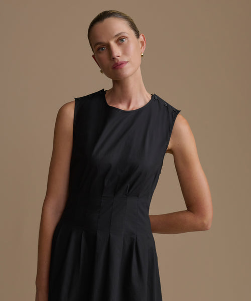 Woman wearing a black sleeveless dress against a beige background