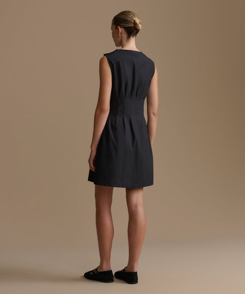 Woman wearing a black dress against a beige background