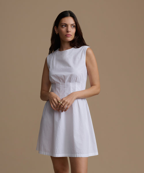 Woman wearing a white dress against a beige background