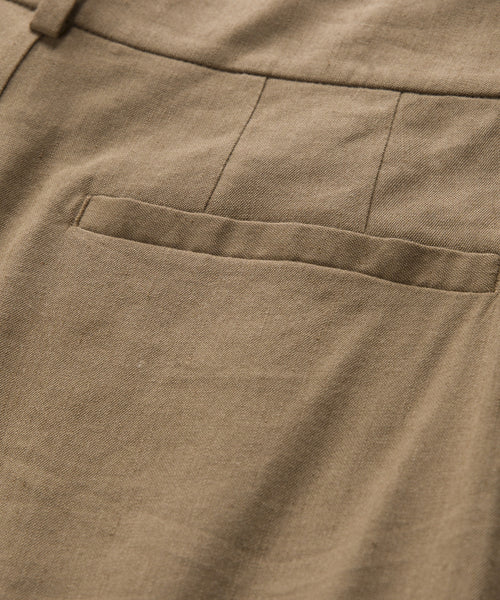Close-up of the Riley Trouser in light brown linen, featuring a neatly stitched seam and pocket. Its lightweight fabric offers airy comfort, making it perfect for summer wear.