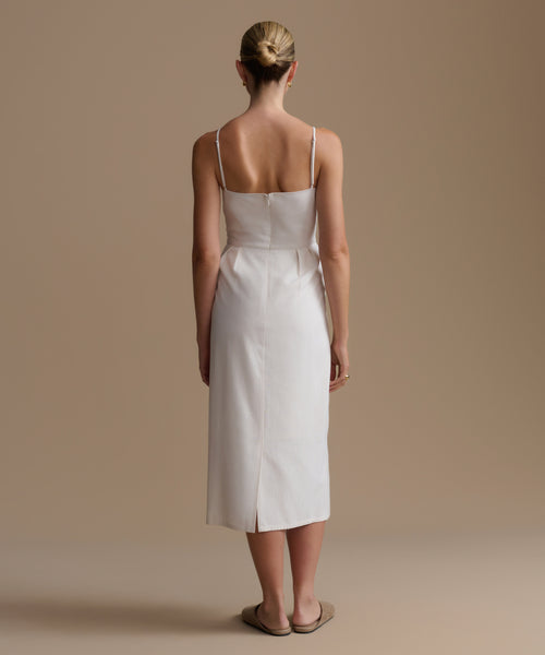 Woman wearing a white dress against a beige background