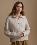 Woman wearing a beige knitted cardigan against a brown background