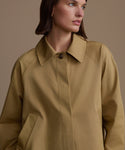 Woman wearing a beige coat against a neutral background