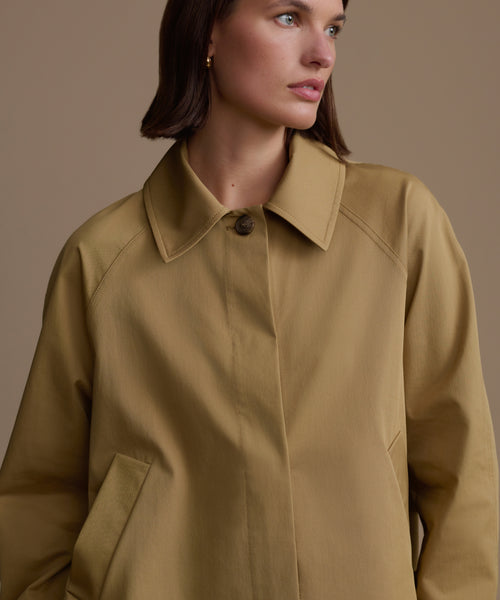 Woman wearing a beige coat against a neutral background