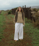 Person standing in a field with wooden posts and a cloudy sky