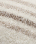 Close-up of the Sheridan Pillow’s soft, textured fabric with cream and light brown horizontal stripes. Thick, woolly fibers resemble alpaca blend yarn, giving this pillow a warm and cozy look.