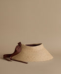 Straw visor with a brown ribbon on a beige background