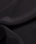 Close-up of smooth, black fabric with soft folds and a matte finish, highlighting the lightweight elegance of the Silk Sloane Shirt—perfect for a relaxed fit.