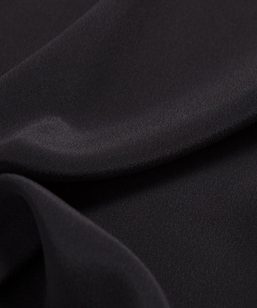 Close-up of smooth, black fabric with soft folds and a matte finish, highlighting the lightweight elegance of the Silk Sloane Shirt—perfect for a relaxed fit.