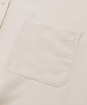 Close-up of the Silk Sloane Shirt in cream-colored sandwashed silk, showing a single chest pocket and part of an ivory button on the left side.