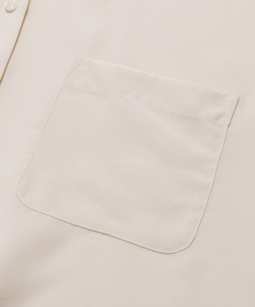 Close-up of the Silk Sloane Shirt in cream-colored sandwashed silk, showing a single chest pocket and part of an ivory button on the left side.