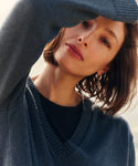 Woman wearing a navy v-neck sweater outside. 