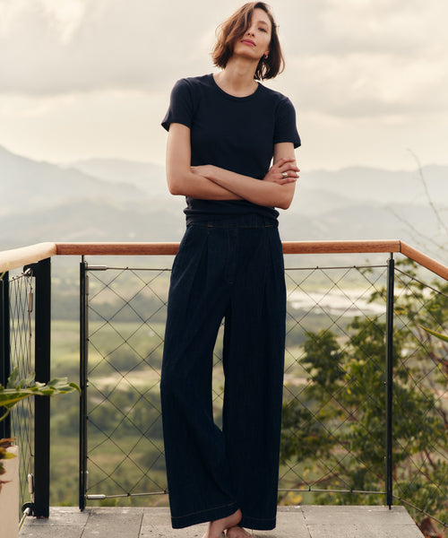 Woman wearing a navy blue t-shirt and pants standing outside.