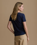 Woman wearing a navy blue t-shirt and beige pants against a brown background