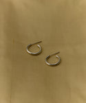 A pair of Small Eloise Hoops in silver is displayed on a light beige fabric background.
