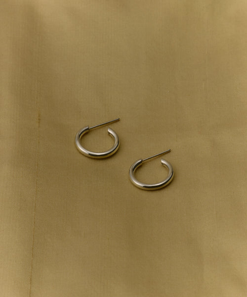 A pair of Small Eloise Hoops in silver is displayed on a light beige fabric background.