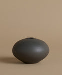 Black ceramic vase on a beige background