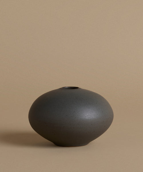 Black ceramic vase on a beige background
