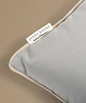 Gray pillow with a Jenni Kayne label on a beige background