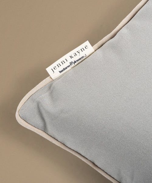 Gray pillow with a Jenni Kayne label on a beige background