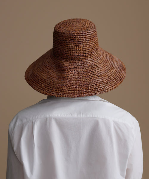 Person wearing a chocolate soleil hat with a plain background