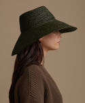 Woman wearing a Olive Soleil hat against a beige background