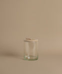 A glass canister against a beige background.